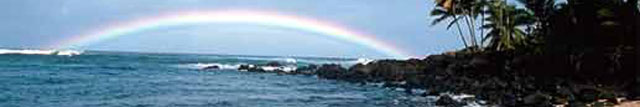 Rainbow over the ocean, waves breaking on rocky beach